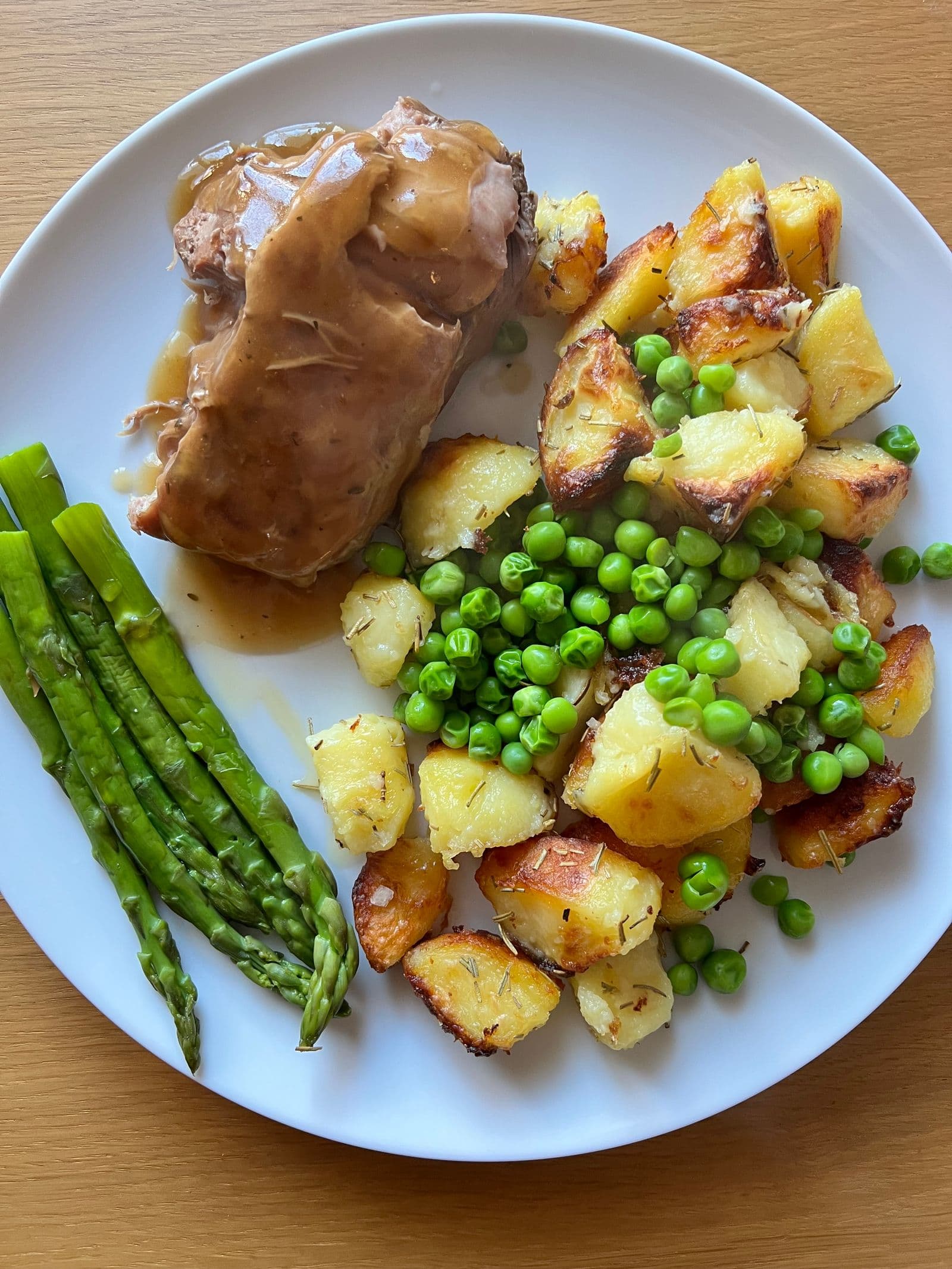 A home-cooked roast dinner with vegetables, plated on a wooden table